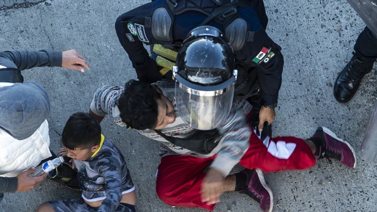 Mexican police stop migrants as they reach the El Chaparral border crossing