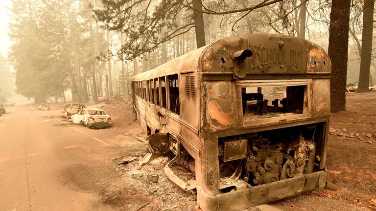 Abandoned burned-out cars and school bus sit on the side of a road in Paradise, California