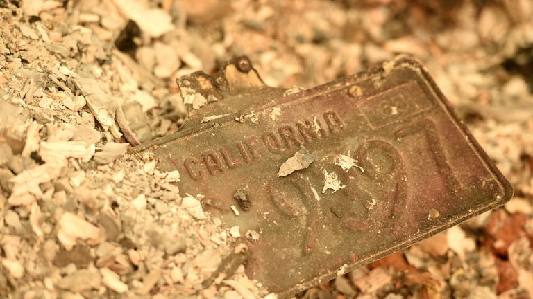 A car number plate partly buried in the remains of the town of Paradise
