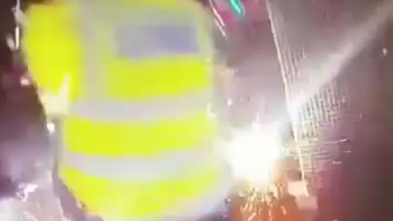 Police officers in Enfield move quickly as a firework is thrown at them in the street