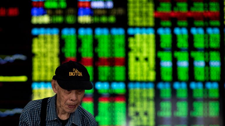 An investor walks past stock prices monitors at a securities company in Shanghai on September 25, 2018