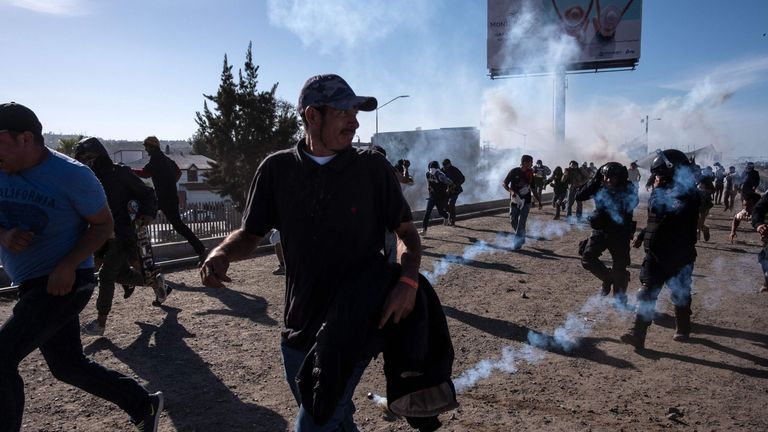 Migrants run along the Tijuana River after the US border patrol throw tear gas 