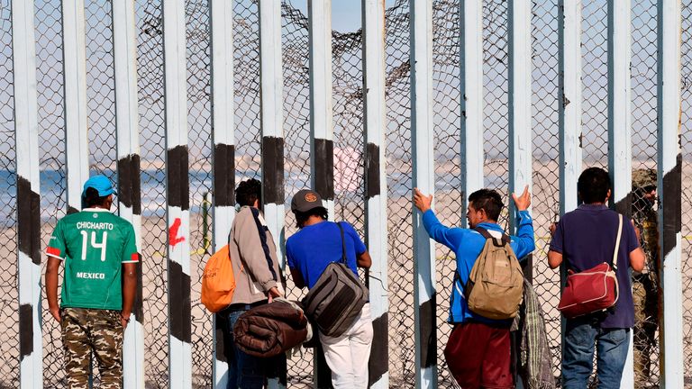 Migrants from the caravan heading from central America look at the US through the border fence
