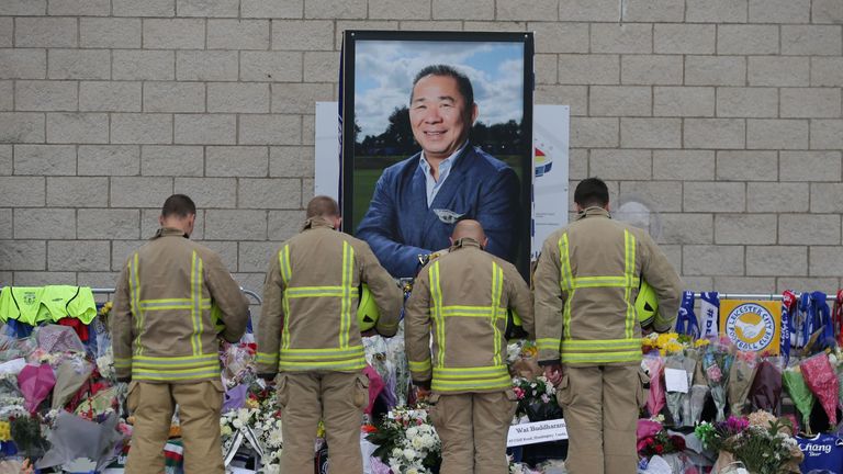 Firefighters pay their respects in front of a portrait of Vichai Srivaddhanaprabha