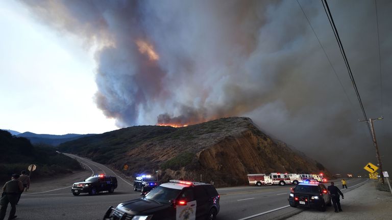 Law enforcement controls traffic along Pacific Coast Highway as the Woolsey Fire advances toward the ocean in Malibu