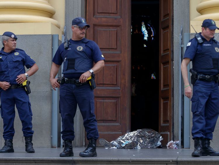 Municipal guards stand next to a covered body at the entrance of the Cathedral of Campinas