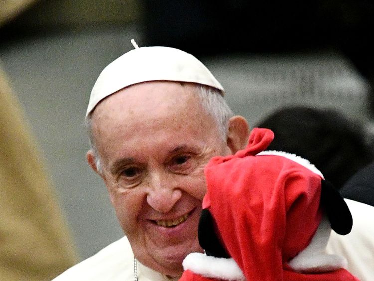 Pope Francis holds a baby wearing a Christmas outfit, and poses for photos during an audience for children and families of the Santa Marta dispensary on December 16, 2018 at the Vatican