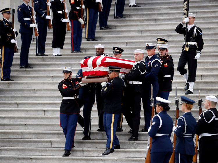 The flag-draped casket of former President George H.W. Bush is carried by a joint services military honour guard from the U.S. Capitol