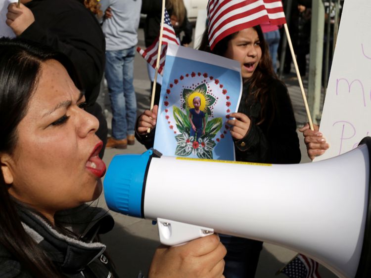 A woman holds a picture of Jakelin Caal, who died in US custody after crossing illegally from Mexico to the US