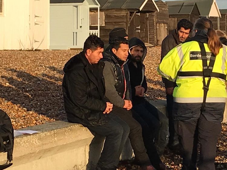 A Border Force official with suspected migrants on the beach at Kingsdown, Kent