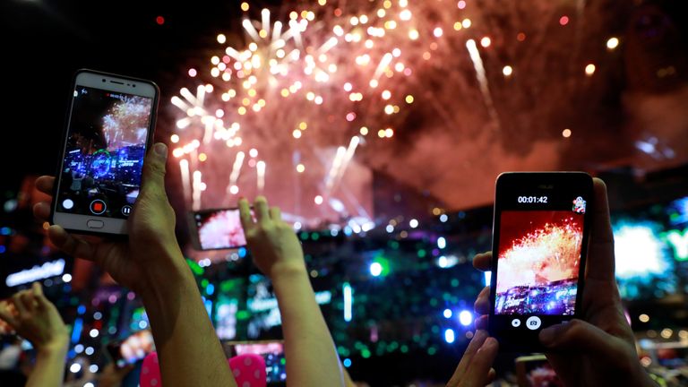 Tourists and locals watch fireworks as they attend the New Year's countdown party in Bangkok, Thailand