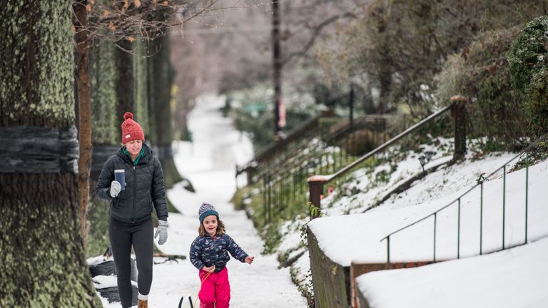 Lauren (L) and Anna Farnham take a walk through the snow in their neighborhood on December 9, 2018 in Charlotte, North Carolina