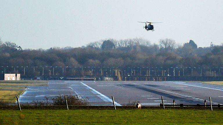 A police helicopter flies over the runway at Gatwick airport which was closed after drones were spotted over the airfield 