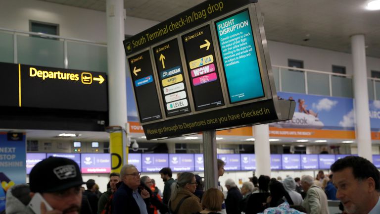 Passengers walk beneath screens displaying travel information in Gatwick Airport, in Crawley, Britain, December 22, 2018