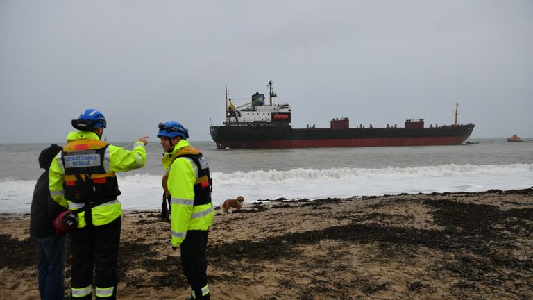 Rescue workers stand on the shore as the refloat operation takes place