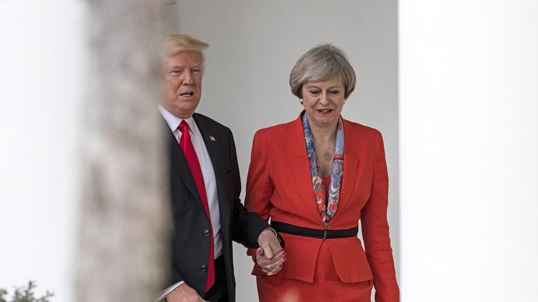 Theresa May and Donald Trump hold hands as they walk along The Colonnade at The White House