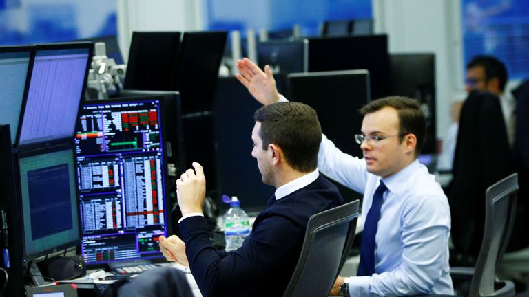 Traders work at their desks whilst screens show market data at CMC Markets in London 13/12/2018