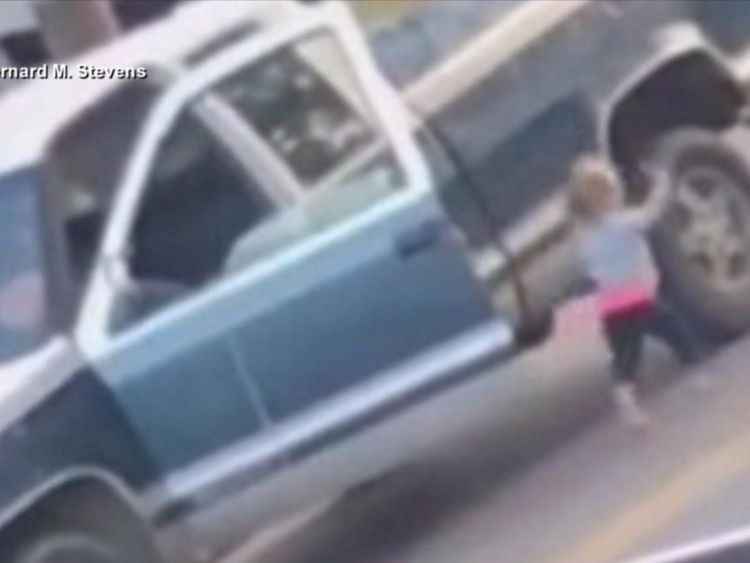 Barefoot toddler walks toward police with hands up while imitating arrested father