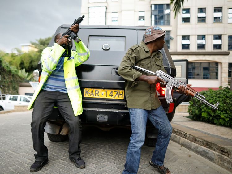 Kenyan security officers take cover behind a moving vehicle as they search for attackers