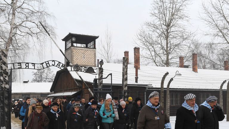 Former prisoners and officials pass the main gate of the Auschwitz concentration camp