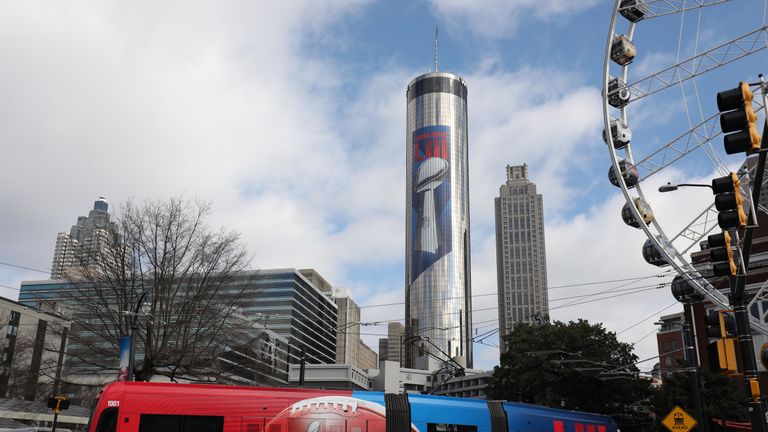 The Atlanta streetcar is shown with Super Bowl LIII banners as it travels below the Westin Peachtree Plaza