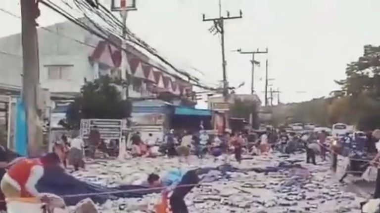 Locals in Rassanda in Phuket, Thailand, assist in the clearing of beer cans, spilled from an overturned truck
