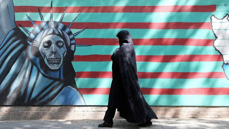Μια ιρανική γυναίκα περπατά πέρα ​​από μια αντι-αμερικανική τοιχογραφία 