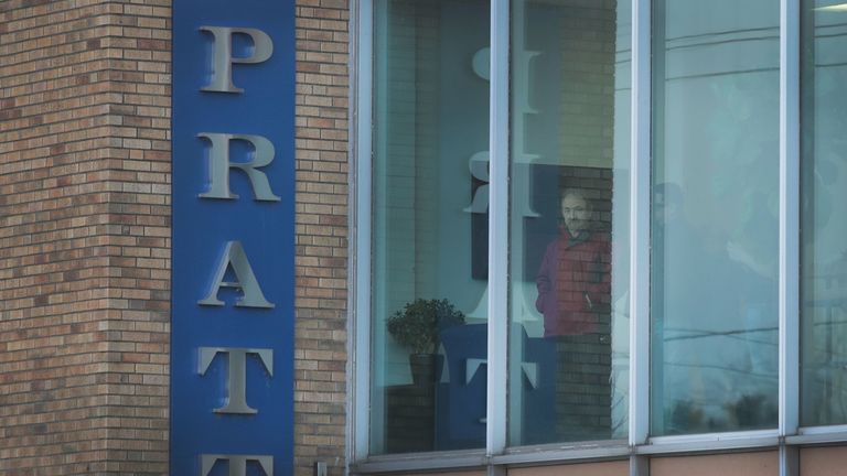 Workers look out an office window following a shooting at the Henry Pratt Company