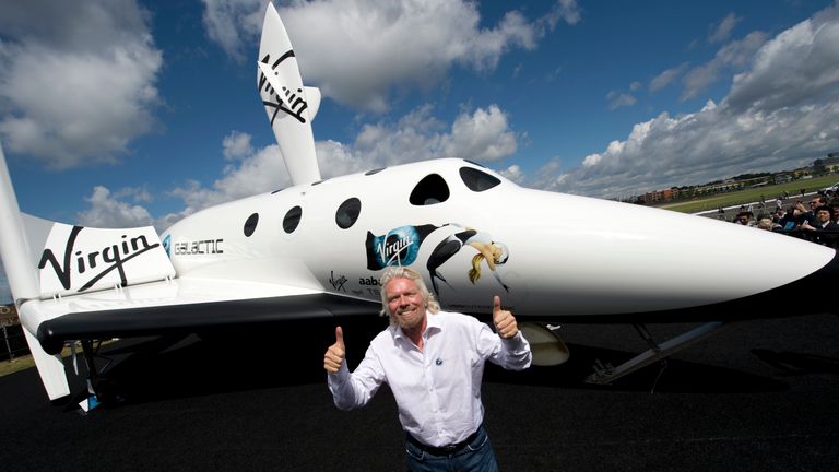 Richard Branson poses in front of a model of the Virgin Galactic spacecraft in 2012