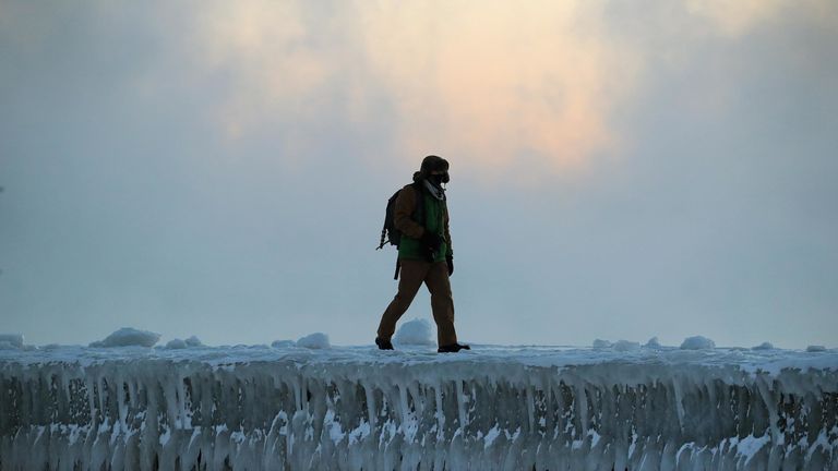 A man walks along an ice-covered break-wall along Lake Michigan near Chicago
