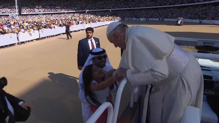 A girl sneaks under the security barrier as she runs towards Pope and hands him a piece of paper during his visit in Abu Dhabi.