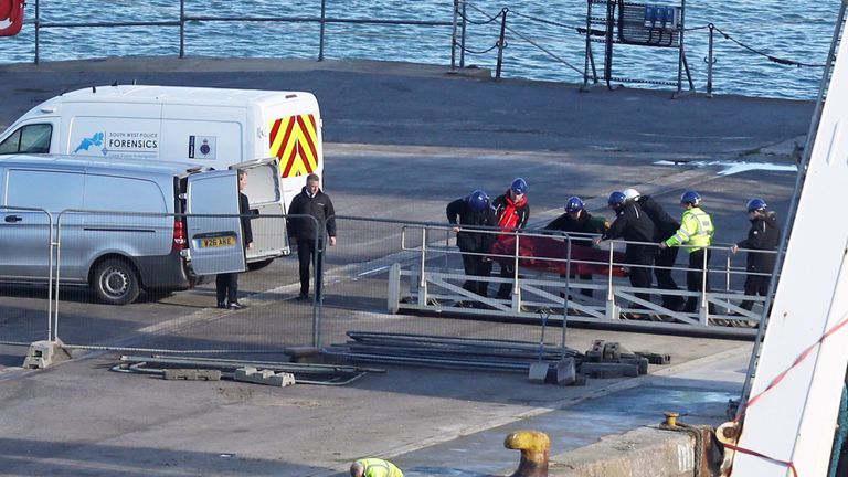 A stretcher carrying a body is removed from the Geo Ocean III specialist search vessel docked in Portland, Dorset 