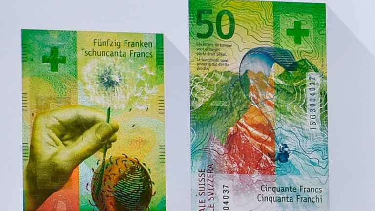 A man silhouettes against an image of the new fifty Swiss franc banknote during its presentation by the Swiss National Bank on April 6, 2016 in Bern. 