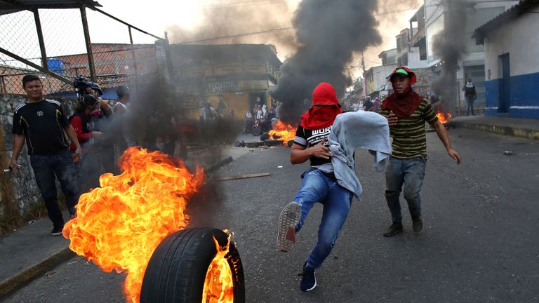 A demonstrator kicks a burning tyre in Urena