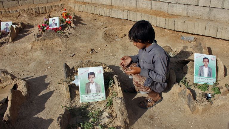 A Yemeni child recites a prayer by the graves of schoolboys who were killed while on a bus that was hit by a Saudi-led coalition air strike