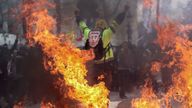 A man wearing a joke Emmanuel Macron mask on his back takes part in the protests