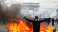 A protester stands in front of a burning barricade on the Champs-Elysees