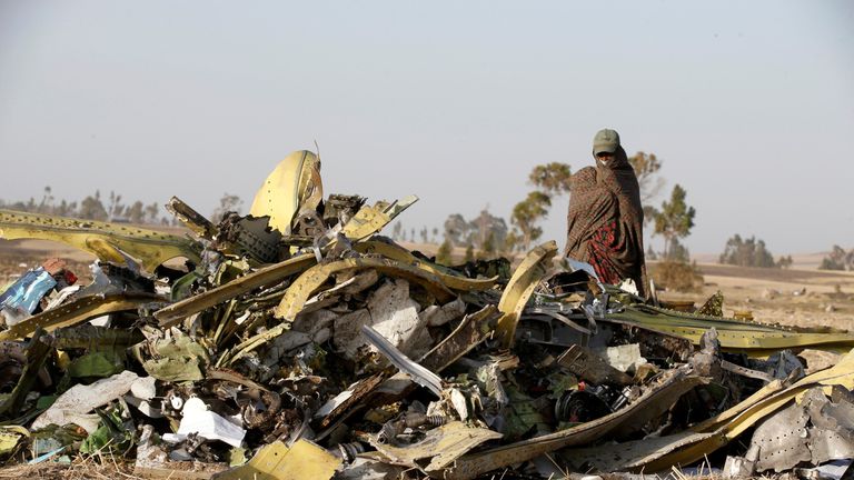 A woman stands near a pile of debris from the Ethiopian Airlines wreckage