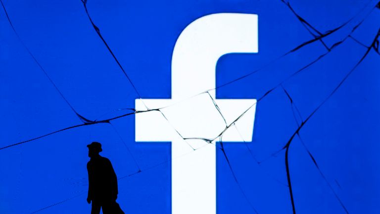 This photograph taken on May 16, 2018, shows a figurine standing in front of the logo of social network Facebook on a cracked screen of a smartphone in Paris