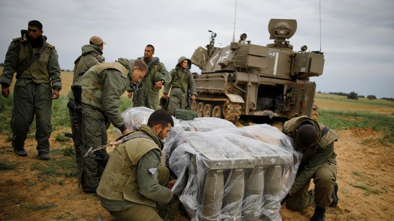 Israeli soldiers cover shells near the Gaza border
