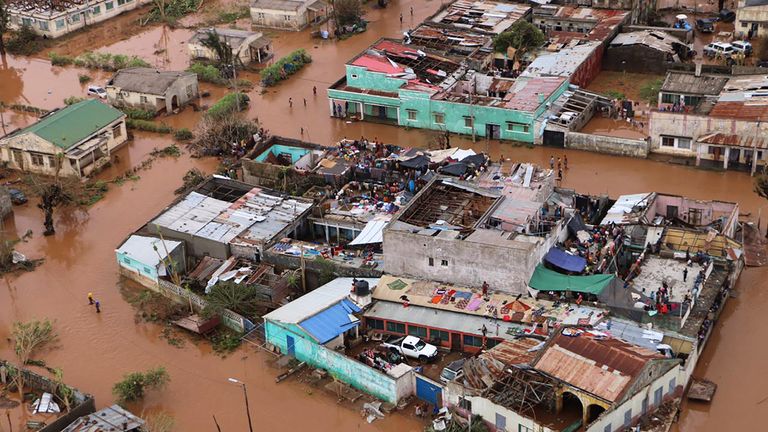 Residents stand on rooftops in a flooded area of Buzi, central Mozambique