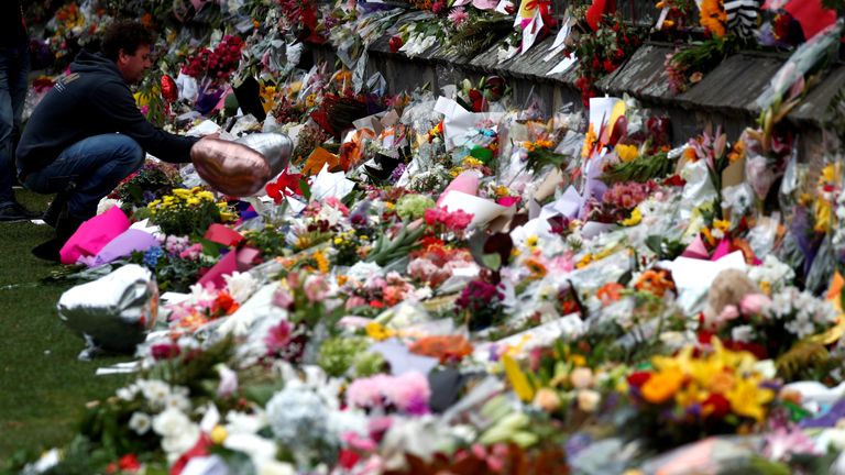 A man lays flowers for victims of the terror attacks at a memorial in Christchurch