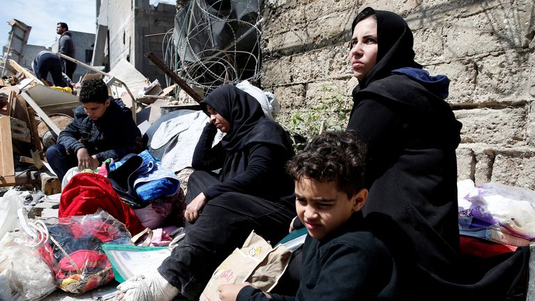 Palestinians sit with their belongings in a street outside their destroyed house