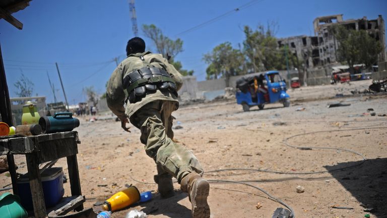 A Somali soldier runs for cover at the scene of two explosions set off near the ministries of public works and labour