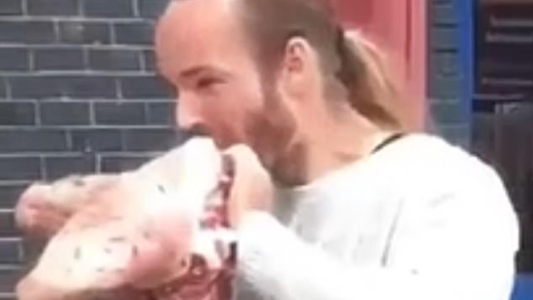 An anti-vegan protester takes bites out of a pig&#39;s head outside VegFest
