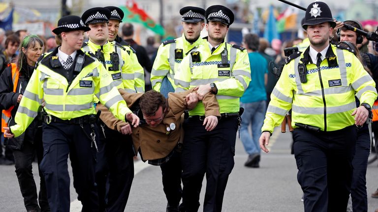 Police officers detain a climate change activist at Waterloo Bridge during the Extinction Rebellion protest in London