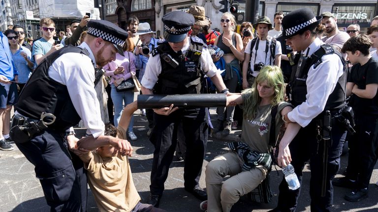 Police try to move climate activists who have glued their hands to a pipe in Oxford Circus