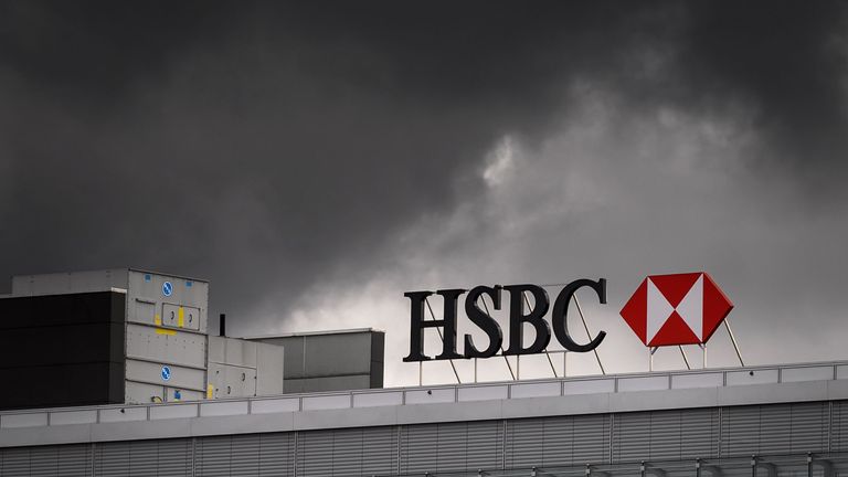 A sign of international banking and financial services holding company HSBC is seen under black clounds on the top of a building on March 1, 2019 in Geneva
