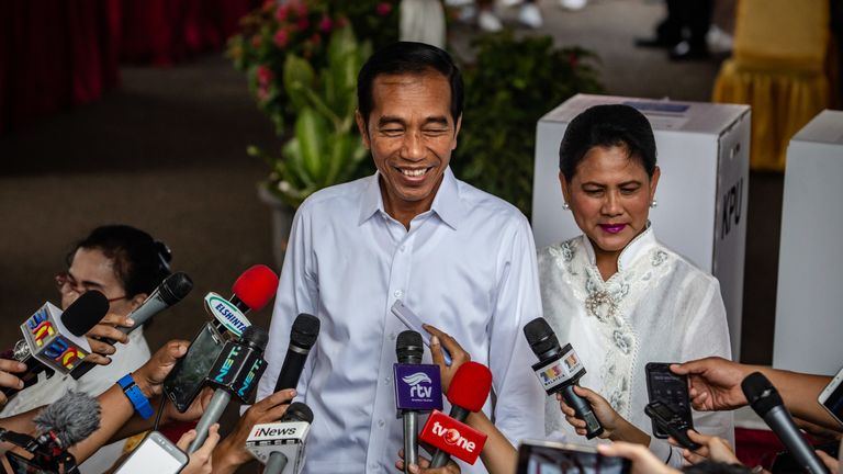 Indonesian President Joko Widodo and his wife Iriana speak to journalists after he cast his ballot