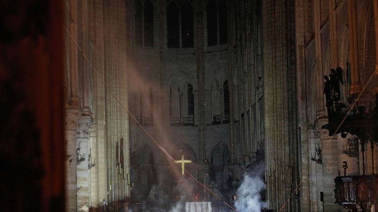 Smoke rises around the altar in front of the cross inside the Notre Dame
